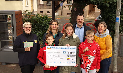 Bürgermeister Sacha Reichelt und Melanie Barth stehen gemeinsam mit Erwachsenen und Kindern aus Horrheim und einem Scheck über 1300 Euro auf dem Luisenplätzchen. 