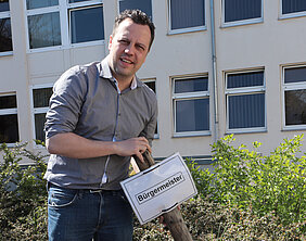 Bürgermeister Sacha Reichelt entfernt das Schild, das bisher den Parkplatz des Bürgermeisters gekennzeichnet hat.