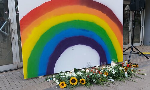 Regenbogen mit Kerzen und Blumen bei der Gedenkveranstaltung
