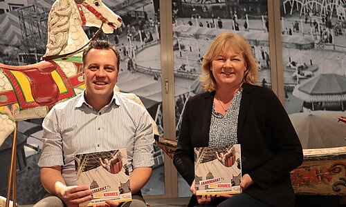 Bürgermeister Sacha Reichelt und die Museumsleiterin mit dem Ausstellungskatalog in der Ausstellung zur Geschichte der Kirmes. 