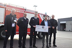 Vertreter der Stadt Euskirchen mit Feuerwehrleuten vor einem Feuerwehrfahrzeug an der Feuerwache in Euskirchen.