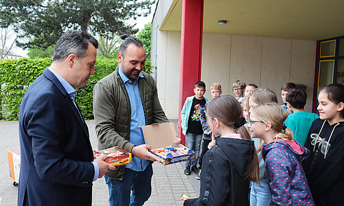 Bürgermeister Sacha Reichelt und Salih Yavuz verteilen Süssigkeiten an die Kinder der GGS Nordstadt.