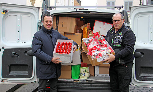 Euskirchens Bürgermeister nimmt eine Spende vor einem vollen Lieferwagen entgegen.