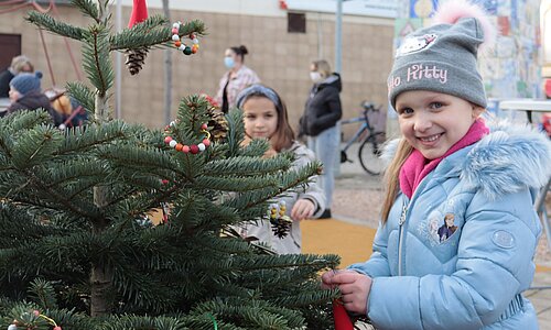 Ein Mädchen schmückt einen Weihnachtsbaum am Rüdesheimer Platz in Euskirchen. 