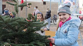 Ein Mädchen schmückt einen Weihnachtsbaum am Rüdesheimer Platz in Euskirchen.