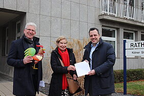 Euskirchens Bürgermeister und Erster Beigeordneter mit einer Spenderin vor dem Rathaus.